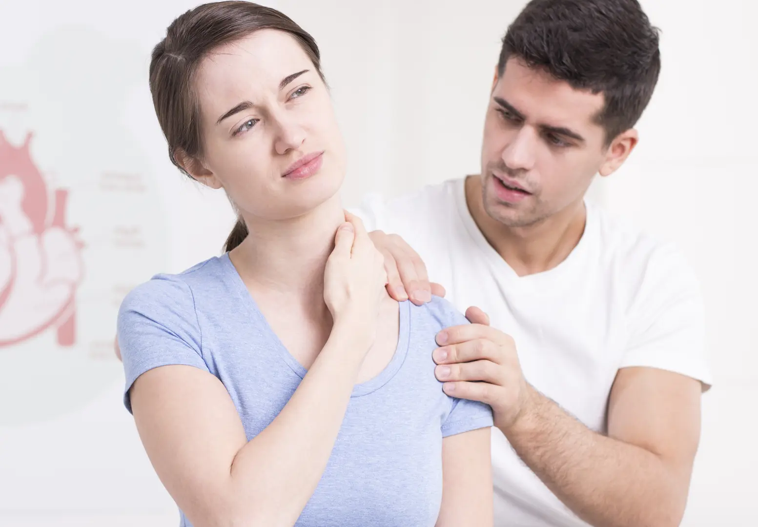 Photo of a young woman in pain, having her shoulder rehabilitated by a handsome PT